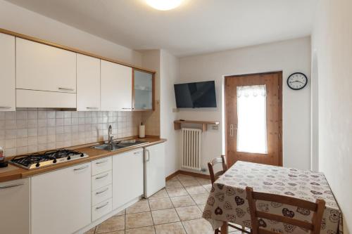 a kitchen with white cabinets and a table with a tablecloth at Dolomitihouse CASTAGNER in Fiera di Primiero