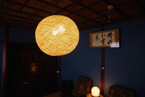 a lamp hanging from a wall with chairs and a clock at Chikugo Yoshii Guest House IKUHA - Vacation STAY 00074v in Ukiha