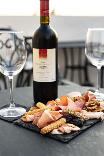 a bottle of wine next to a plate of meat and corn at The Oscar Olympic Hotel in Thessaloniki