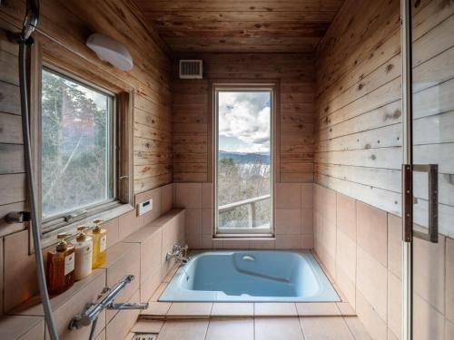 a bathroom with a tub in a room with a window at Oceanic House TAMATEBAKO - Vacation STAY 98444 in Ito