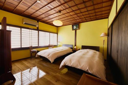 two beds in a room with yellow walls at Chikugo Yoshii Guest House IKUHA - Vacation STAY 00064v in Ukiha