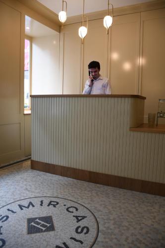 a man talking on a phone behind a counter at Hôtel Casimir in Paris