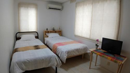 a bedroom with two beds and a television in it at Guest House Mulberry - Vacation STAY 9580 in Kirishima