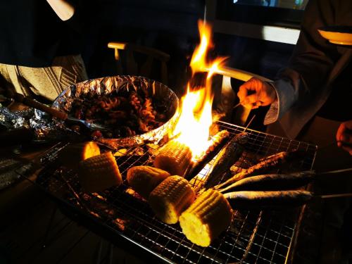 a man cooking food on a grill with a fire at Nasusanso - Vacation STAY 9643 in Nasu-yumoto