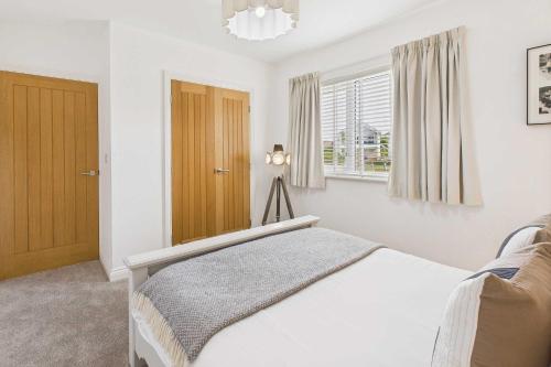 a white bedroom with a bed and a window at Host & Stay - Bayview Lodge in Beadnell