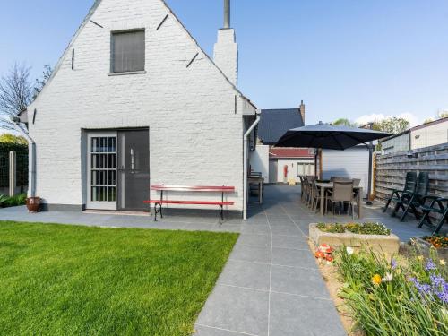 a white house with a patio with a bench and a table at Farmhouse in Beveren near Beach & Garden in Beveren