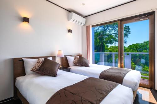due letti in una stanza con una grande finestra di KOURI Ocean Moon Cottage - Vacation STAY 05891v a Kouri