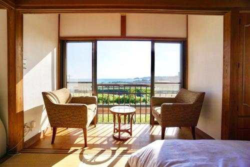 a bedroom with two chairs and a table and a large window at and SEA Kamogawa - Vacation STAY 07561v in Kamogawa