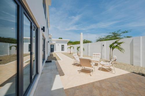 a patio with chairs and a table next to a building at 5BR Villa with Pool & Patio at Casa Eloisa by Bocobay in Oranjestad