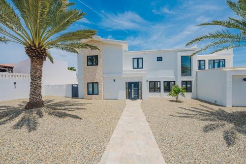 a white house with a palm tree in front of it at 5BR Villa with Pool & Patio at Casa Eloisa by Bocobay in Oranjestad