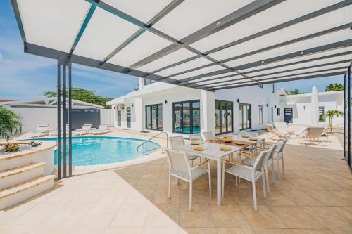 a patio with a table and chairs and a pool at 5BR Villa with Pool & Patio at Casa Eloisa by Bocobay in Oranjestad