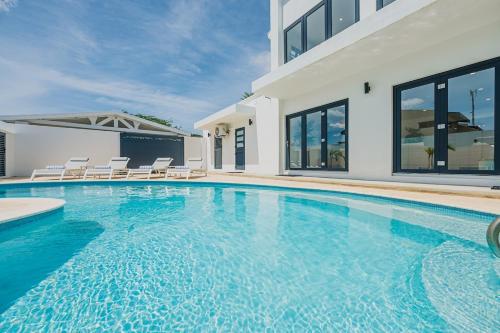 a swimming pool with chairs and a house at 5BR Villa with Pool & Patio at Casa Eloisa by Bocobay in Oranjestad