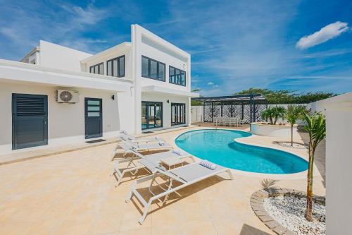 a villa with a swimming pool and lounge chairs at 5BR Villa with Pool & Patio at Casa Eloisa by Bocobay in Oranjestad