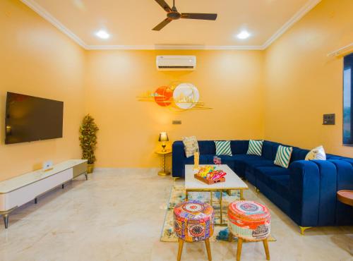 a living room with a blue couch and a tv at The Bliss Hushwood 2-BHK Villa With Private Pool, Lush Garden & Poolside Gazebo Pet-friendly in Udaipur