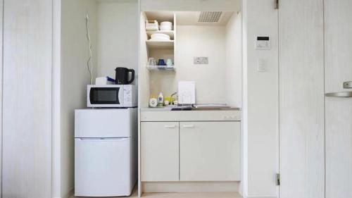 a white kitchen with a refrigerator and a microwave at Marvelous Higashioi - Vacation STAY 13015v in Tokyo