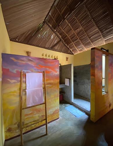 a room with a painting on the wall and a ladder at Hazotsara Guest House in Nosy Be