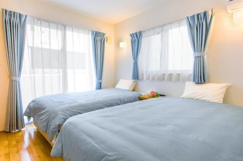two beds in a bedroom with blue curtains at Chatan villa Uminosoba - Vacation STAY 08585v in Hamakawa