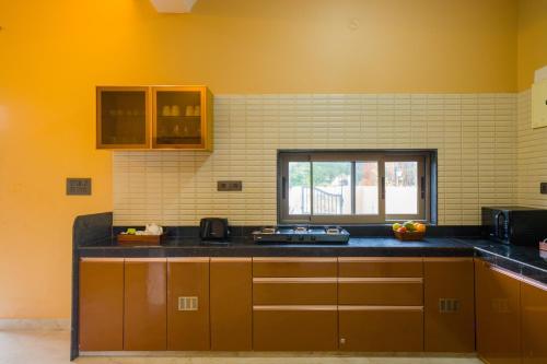 a kitchen with yellow walls and a counter top at The Bliss Hushwood 2-BHK Villa With Private Pool, Lush Garden & Poolside Gazebo Pet-friendly in Udaipur