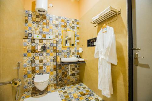 a bathroom with a toilet and a tiled wall at The Bliss Hushwood 2-BHK Villa With Private Pool, Lush Garden & Poolside Gazebo Pet-friendly in Udaipur