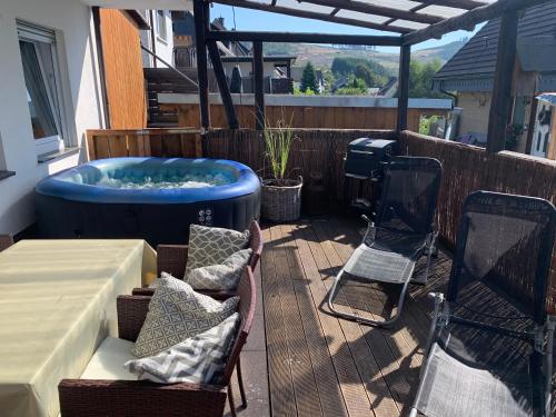 a patio with a hot tub and a table and chairs at Ferienwohnung Bergblick in Winterberg