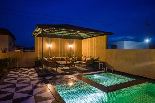 a patio with a swimming pool at night at The Bliss Hushwood 2-BHK Villa With Private Pool, Lush Garden & Poolside Gazebo Pet-friendly in Udaipur