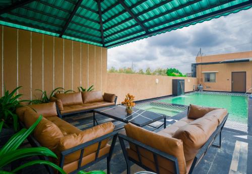 a swimming pool with leather furniture and a swimming pool at The Bliss Hushwood 2-BHK Villa With Private Pool, Lush Garden & Poolside Gazebo Pet-friendly in Udaipur