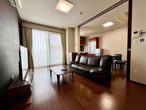 un salon avec un canapé en cuir et une table dans l'établissement Hamamoto Palace Taniyama - Vacation STAY 11965, à Kagoshima