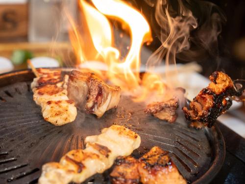 a steak on a grill with fire in it at Farm Garden Hotel in Numazu