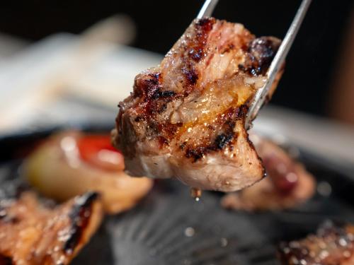 a person holding a piece of meat on a fork at Farm Garden Hotel in Numazu