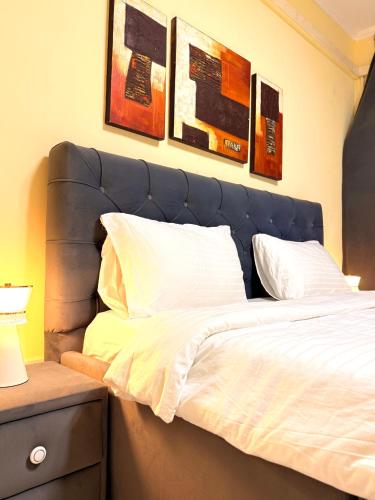 ルアンダにあるCharming Apartment in Historic Building-Near Luanda Bayの青いヘッドボードと壁にいくつかの絵が飾られたベッド