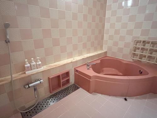 a bathroom with a pink tub in the floor at Farm Garden Hotel in Numazu