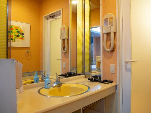 a bathroom with a yellow sink and a mirror at Farm Garden Hotel in Numazu