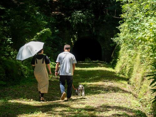 a man and a woman walking a dog in front of a tunnel at Farm Garden Hotel in Numazu