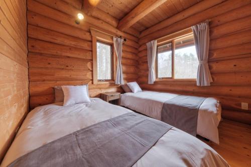a bedroom with two beds in a log cabin at Shakunagedaira Rental Cottage - Vacation STAY 18468v in Numajiri