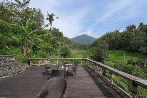 a table and chairs on a wooden deck with a view at Keuma Villa & Resto Jatiluwih by The Lavana in Jatiluwih