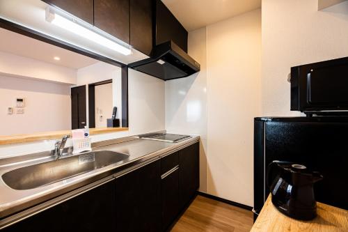 a kitchen with a sink and a black refrigerator at Tomariehoteru & kondominiamu - Vacation STAY 19483v in Hakata