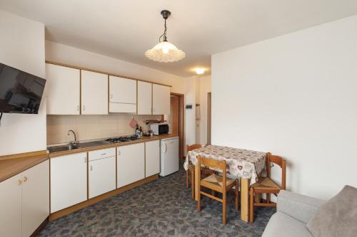 a kitchen with white cabinets and a table with chairs at Dolomitihouse AVET in Fiera di Primiero