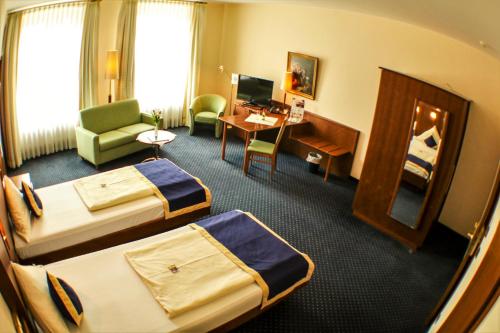 a hotel room with two beds and a desk at Victoria Hotel in Minden