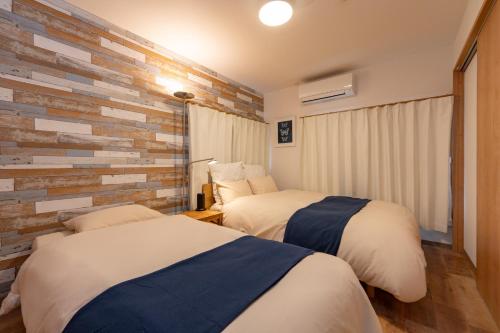 a bedroom with two beds and a brick wall at Shinjuku-ku - House - Vacation STAY 17230 in Tokyo