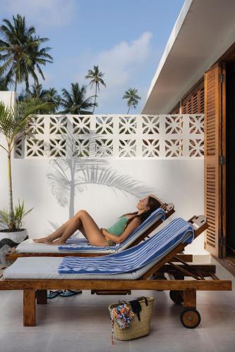 a woman laying on a lounge chair on a beach at ZAN Orient Beach Hotel in Bwejuu