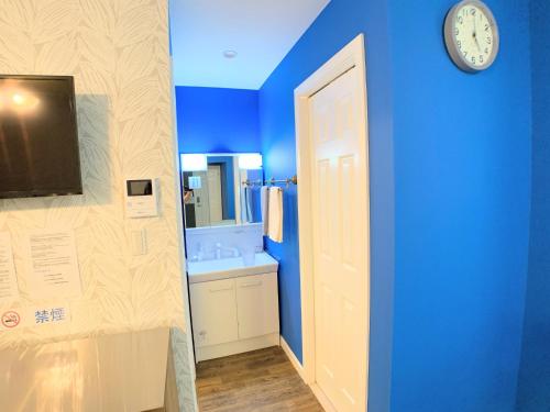 a bathroom with a clock on a blue wall at Alaula - Vacation STAY 22838v in Izumi-Sano