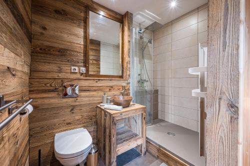 a bathroom with wooden walls and a toilet and a shower at L'Escampette à la Fontanette in Saint-Pancrace
