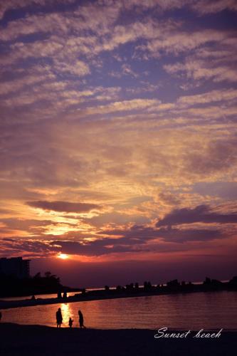 a sunset at the beach with people walking on the beach at STEP by STEP - Vacation STAY 25753v in Kanayama