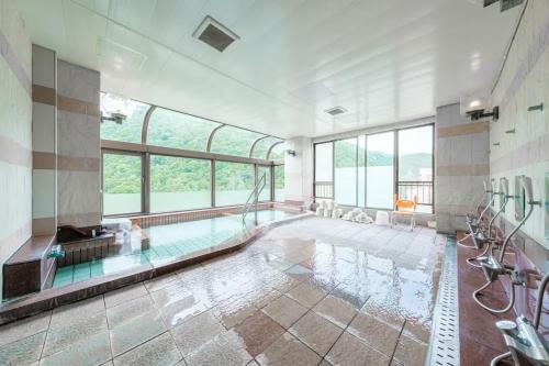a large bathroom with a swimming pool with windows at Lions Mansion Sapporo Jozankei Sanbankan - Vacation STAY 10916 in Jozankei