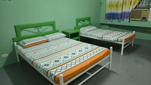 two beds in a room with green walls at Green Mellow Court Osmena in Dipolog