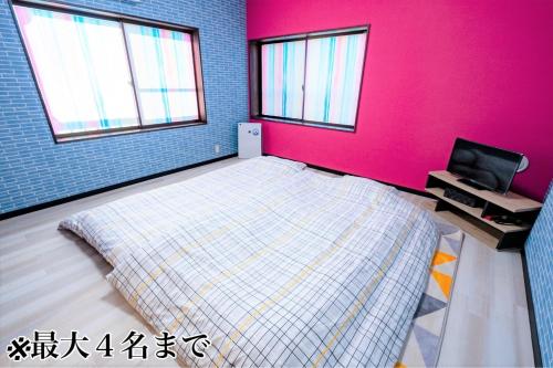 a bedroom with a bed and a pink wall at STEP by STEP - Vacation STAY 25756v in Kanayama