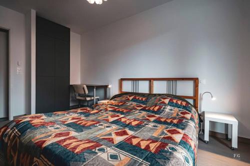 a bedroom with a bed with a colorful quilt at Le Doran - Terrasse & Vue Mont Blanc in Sallanches