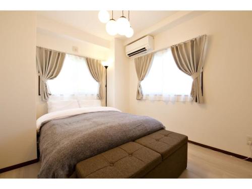 a bedroom with a bed and two windows at Ocean Terrace Sesoko 101 - Vacation STAY 28609v in Ufugumui
