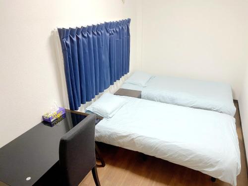 a room with two beds and a desk and blue curtains at SKYE HOME MINPAKU - Vacation STAY 11856 in Tokyo