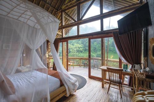 a bedroom with a canopy bed and a balcony at Keuma Villa & Resto Jatiluwih by The Lavana in Jatiluwih